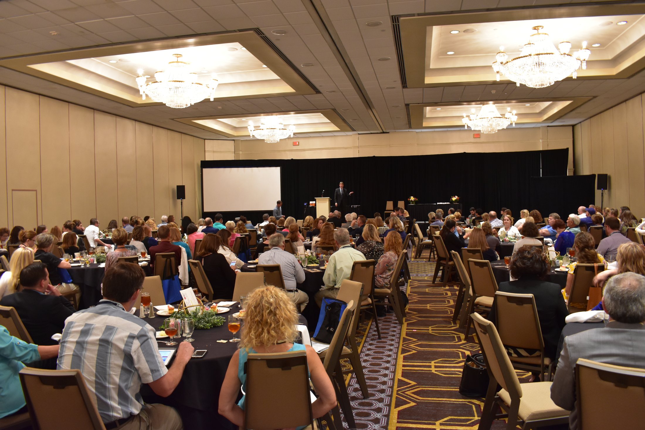 A keynote speaker addresses school leaders in a packed hotel ballroom at a NAUMS gathering