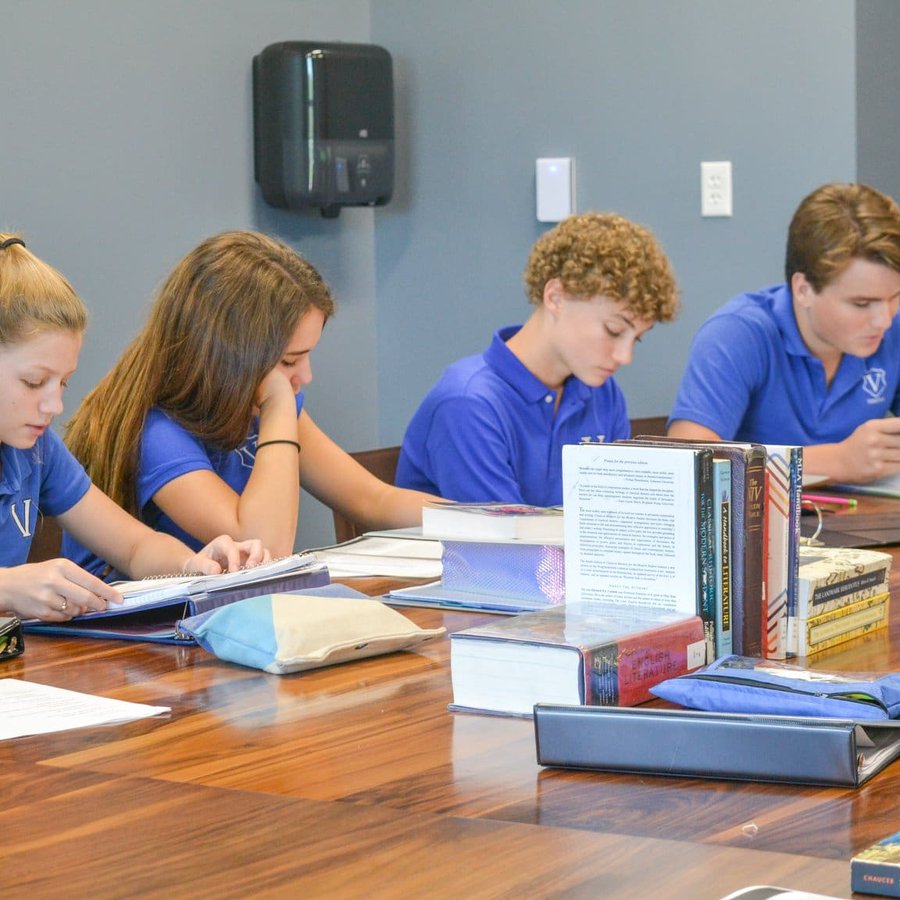Veritas Academy students studying together around a table stacked with books